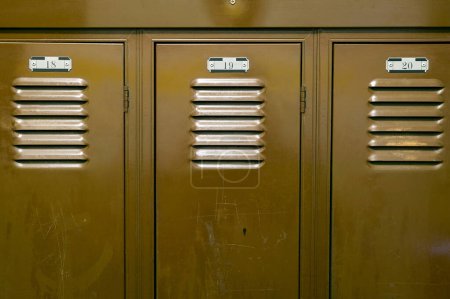 A close up of steel storage locker cupboards showing the locker room numbers.