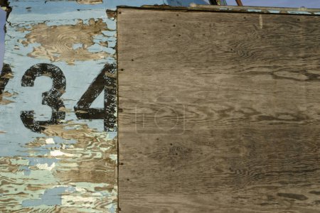 Photo for Old weathered wood background with black paint stencilled number 34 on peeling lighter colored paint and woodgrain texture - Royalty Free Image