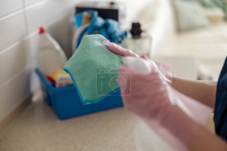 Foto de El primer plano de las manos de la mujer limpia la mesa de trabajo, usa trapo y productos de detergente efectivos en la cocina. - Imagen libre de derechos