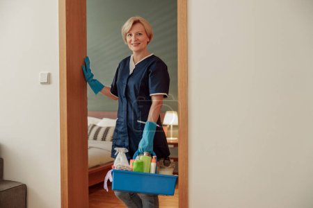 Foto de La señora de la limpieza profesional sostiene la caja con detergentes y trapos y cámara de aspecto. Foto de alta calidad - Imagen libre de derechos