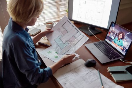 Foto de Primer plano de la mujer diseñador de interiores de verificación de documentos mientras se trabaja de forma remota desde la oficina en casa - Imagen libre de derechos