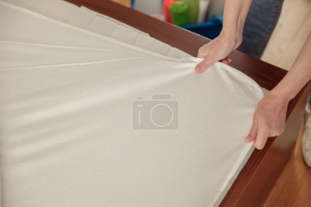 Foto de Mujer está poniendo la cubierta de ropa de cama o colchón almohadilla en la cama o posponer para el proceso de limpieza - Imagen libre de derechos