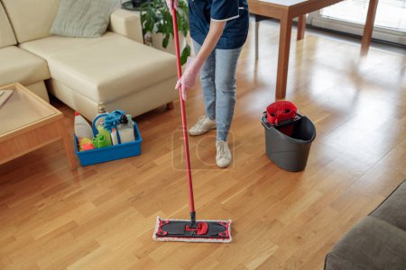 Foto de Mujer lavando piso con fregona en sala de estar utilizando equipo profesional. concepto de limpieza de la casa - Imagen libre de derechos