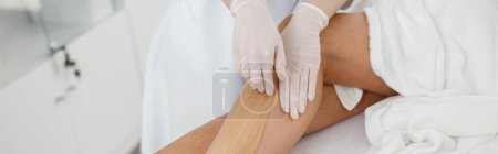 Photo for Woman client having hair removal procedure on leg using sugaring paste in beauty salon, close up - Royalty Free Image