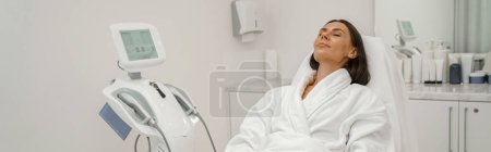 Téléchargez les photos : Femme en peignoir blanc relaxant pendant la procédure médicale en clinique de beauté. Photo de haute qualité - en image libre de droit