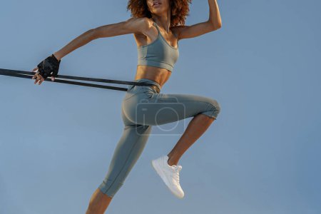Téléchargez les photos : Woman performs exercises with expander on studio background. Strength and motivation - en image libre de droit