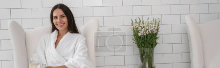 Foto de Mujer en albornoz blanco beber agua durante el procedimiento médico en la clínica de belleza. Foto de alta calidad - Imagen libre de derechos