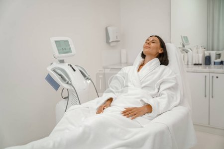 Mujer en albornoz blanco relajante durante el procedimiento médico en la clínica de belleza. Foto de alta calidad