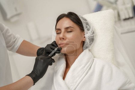 Foto de El cosmetólogo hace las inyecciones para aumentar los labios de la mujer en el salón de belleza. Foto de alta calidad - Imagen libre de derechos
