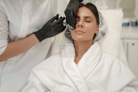 Foto de El cosmetólogo hace las inyecciones para aumentar los labios de la mujer en el salón de belleza. Foto de alta calidad - Imagen libre de derechos