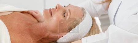 Foto de Vista lateral de relajado de mediana edad hermosa señora paciente acostada en el gabinete de belleza en la sesión de masaje - Imagen libre de derechos