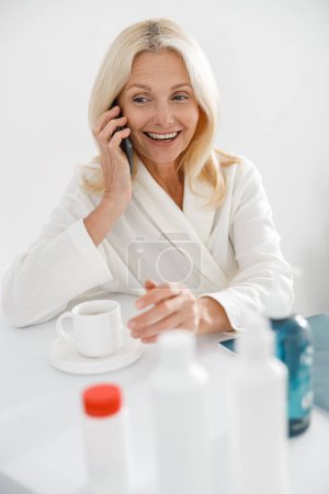 Foto de Retrato de mujer guapa caucásica llamando en el teléfono móvil en el centro de bienestar blanco y sonriendo - Imagen libre de derechos