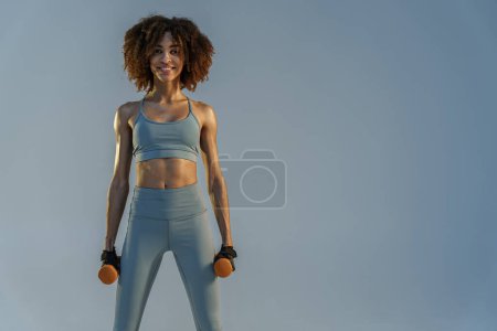 Foto de Retrato de mujer musculosa haciendo ejercicio con pesas pesadas sobre fondo de estudio - Imagen libre de derechos