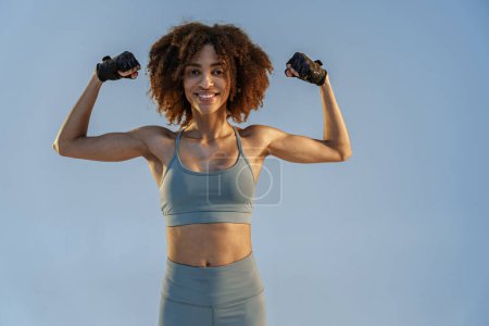 Photo for Woman in sportswear shows off her muscles standing on studio background. Workout results - Royalty Free Image