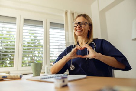 Foto de Médico cardiólogo femenino mostrando el símbolo del corazón con los dedos. Foto de alta calidad - Imagen libre de derechos