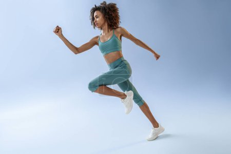Foto de Athletic active woman jumping on studio background. Dynamic movement - Imagen libre de derechos