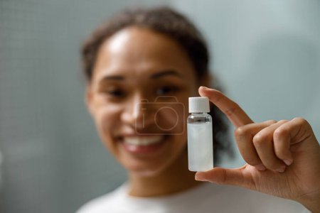 Foto de Mujer sonriente sosteniendo cosméticos naturales para el cuidado de la piel de pie en el baño. Foto de alta calidad - Imagen libre de derechos
