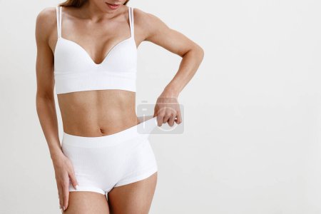 Téléchargez les photos : Slim et beau corps féminin en lingerie blanche sur fond de studio. Photo de haute qualité - en image libre de droit