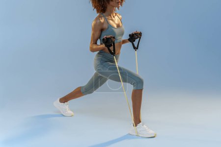 Photo for Close up of woman performs exercises with expander on studio background. Strength and motivation - Royalty Free Image
