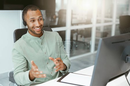 Photo for African businessman in headphones talking online with client sitting in office. Blurred background - Royalty Free Image