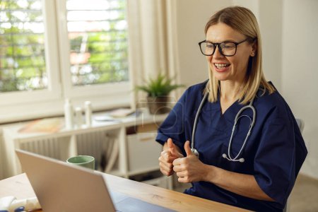 Foto de Médico viendo webinar médico en línea mientras está sentado con el ordenador portátil en la oficina - Imagen libre de derechos