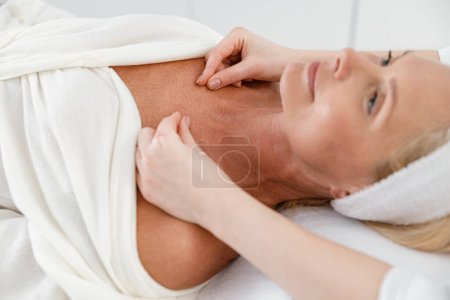 Téléchargez les photos : Heureux adulte assez confiant client féminin se faire masser dans le cabinet de cosmétologue, procédure de spa - en image libre de droit
