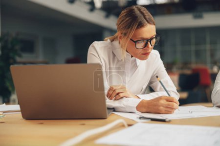 Foto de Mujer gerente haciendo notas en el escritorio en coworking moderno. Foto de alta calidad - Imagen libre de derechos