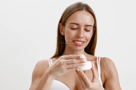 Foto de Mujer vistiendo lencería con frasco de crema facial sobre fondo blanco estudio. Foto de alta calidad - Imagen libre de derechos