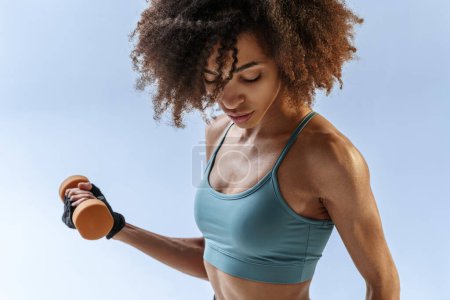 Foto de Mujer haciendo ejercicios con pesas en el fondo del estudio. Deporte y estilo de vida saludable - Imagen libre de derechos