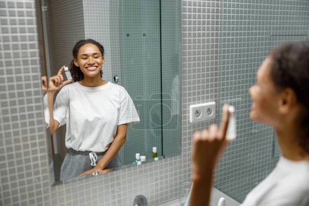 Photo for Smiling woman holding natural skincare cosmetics standing in bathroom. High quality photo - Royalty Free Image