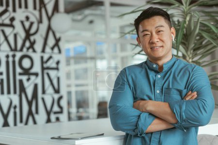 Téléchargez les photos : Portrait d'homme d'affaires asiatique souriant debout dans le bureau. Photo de haute qualité - en image libre de droit