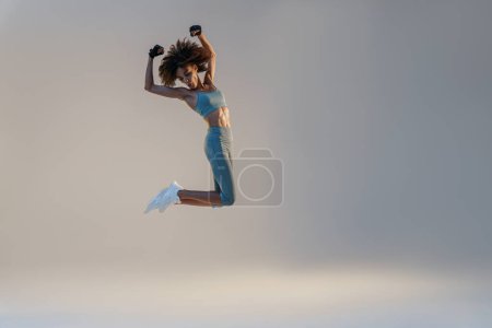 Téléchargez les photos : Femme active athlétique sautant sur fond de studio. Mouvement dynamique - en image libre de droit