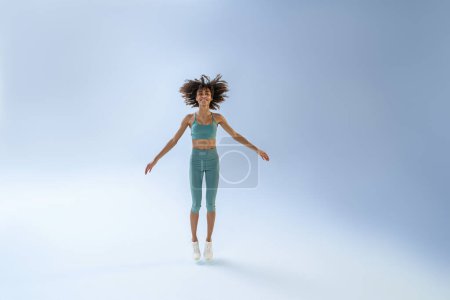 Foto de Athletic active woman jumping on studio background. Dynamic movement - Imagen libre de derechos