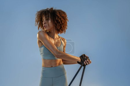 Photo for Woman performs exercises with expander on studio background. Strength and motivation - Royalty Free Image