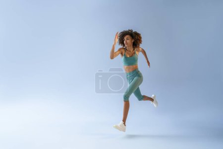 Foto de Atlética mujer activa saltando en el fondo del estudio. Movimiento dinámico - Imagen libre de derechos