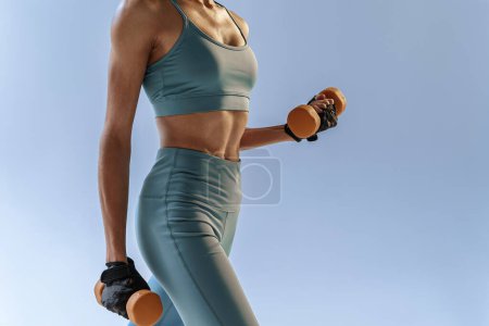 Photo for Woman doing exercises with dumbbells on studio background. Sport and healthy lifestyle - Royalty Free Image