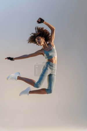 Photo for Athletic active woman jumping on studio background. Dynamic movement - Royalty Free Image