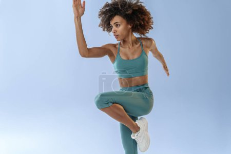 Photo for Athletic active woman jumping on studio background. Dynamic movement - Royalty Free Image