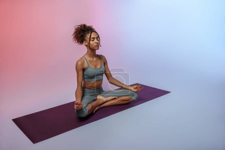 Téléchargez les photos : Fitness femme pratiquant le yoga sur tapis sur fond de studio avec filtre de couleur. Photo de haute qualité - en image libre de droit
