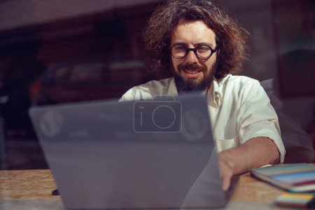 Foto de Freelancer masculino que trabaja en el ordenador portátil mientras está sentado en coworking moderno. Foto de alta calidad - Imagen libre de derechos