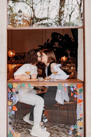 Téléchargez les photos : Couple amoureux embrasser pendant la date tout en étant assis dans le bar et boire du vin. Photo de haute qualité - en image libre de droit