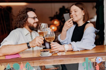 Téléchargez les photos : Couple pendant la date de boire du vin et de faire des photos tout en étant assis dans le bar. Photo de haute qualité - en image libre de droit