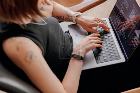 Foto de La programadora escribe código de programa en el portátil mientras está sentada en el coworking moderno. Foto de alta calidad - Imagen libre de derechos