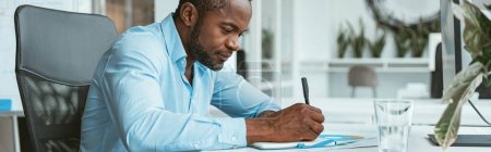 Photo for Confident African businessman taking notes while sitting in modern office. High quality photo - Royalty Free Image