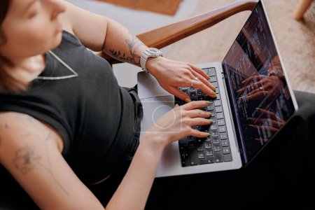 Téléchargez les photos : Programmeur femme écrit le code de programme sur l'ordinateur portable tout en étant assis dans le coworking moderne. Photo de haute qualité - en image libre de droit