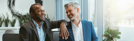 Téléchargez les photos : Deux hommes d'affaires parlent d'un deal assis dans une salle de réunion au bureau. Photo de haute qualité - en image libre de droit