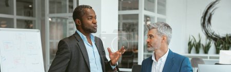 Foto de Dos hombres de negocios hablando de un trato de pie en la sala de reuniones en la oficina. Foto de alta calidad - Imagen libre de derechos