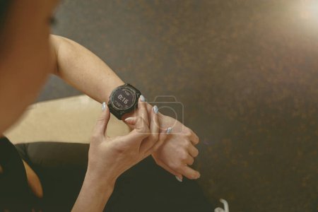 Photo for Close up of woman looking at smartwatch on her wrist while resting after workout. High quality photo - Royalty Free Image