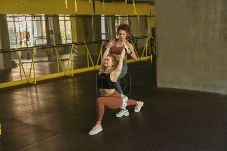 Téléchargez les photos : Fit femme faire des exercices d'étirement avec l'aide d'un entraîneur personnel à la salle de gym. Photo de haute qualité - en image libre de droit