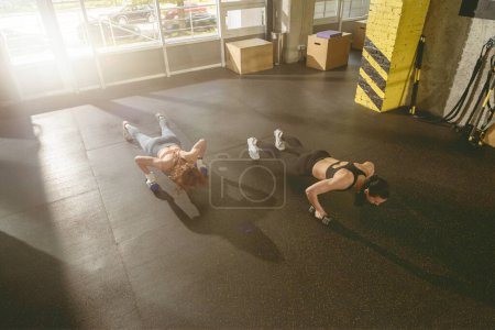 Foto de Dos mujeres haciendo ejercicio de flexiones con mancuerna. Mujeres fuertes haciendo ejercicio. Foto de alta calidad - Imagen libre de derechos